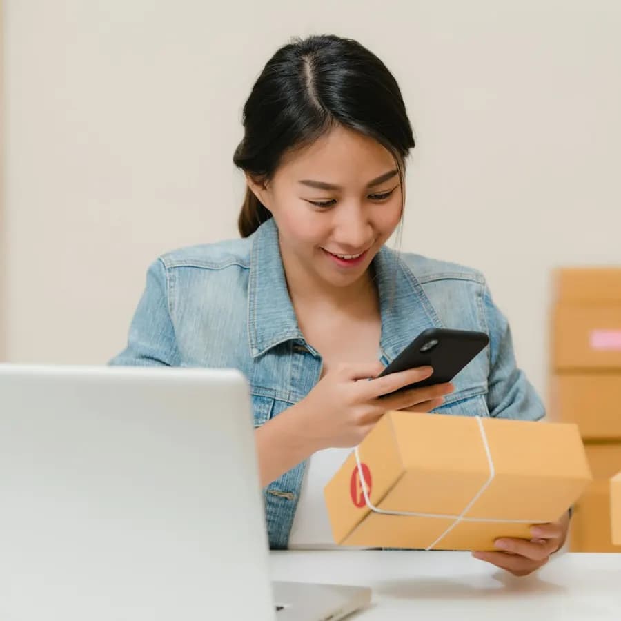Kreator muda mengecek HP sambil menyiapkan konten produk